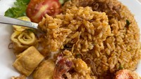 Porsi nasi gorengnya melimpah, berwarna sedikit kemerahan karena menggunakan sambal tomat. Rasanya gurih dan tidak manis, karena kecapnya sedikit. Paduan ayam gorengnya juga mantap, tekstur renyah garing dari kulit ayam menambah selera makan yang ditutup dengan udang goreng tepung. Foto: detikFood