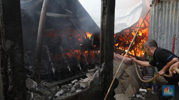 Petugas pemadam kebakaran melakukan pemadaman api yang membakar hudang rental motor listrik MIGO di kawasan  Meruya Bara, Jakarta barat, Senin (24/1/2022). Sebanyak enam mobil damkar dikerahkan dalam insiden ini. Belum ada info resmi dari pemilik gudang. Menurut warga sekitar 