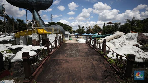 Pekerja melakukan perancangan proyek revitalisasi Taman Mini Indonesia Indah (TMII), Senin (24/1/2022). Snowbay Waterpark dulunya dikenal sebagai wahana favorit anak-anak, sayangnya karena COVID-19, kolam renang dengan berbagai wahana itu harus ditutup selama nyaris 2 tahun. Beberapa kondisi fisik yang terbengkalai terlihat dilokasi ini mulai pintu masuk tiket dan rak tempat penitipan barang. Kondisi Snowbay Waterpark saat ini memang tak terurus karena sudah lama tutup. Sejumlah kolam renang dibiarkan begitu saja hingga airnya keruh. Terlihat juga toko-toko yang dulu menjual perlengkapan renang dan kuliner juga tutup.  Dikutip dari situs tamanmini.com, Snowbay Waterpark mulanya dirancang secara khusus sebagai taman rekreasi petualangan berkelas dunia berkonsep pegunungan saljuTaman seluas 3 hektar ini dibangun tahun 2008 dan diresmikan pembukaannya oleh ketua Yayasan harapan Kita, Hj. Siti Hardiyanti Rukmana pada tanggal 19 April 2009. Sebelumnya, taman ini adalah Taman Rekreasi Ambar Tirta. (CNBC Indonesia/ Tri Susilo)