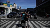 Sejumlah warga melintasi pelican crossing Glodok, Jakarta Barat, Senin (24/1).