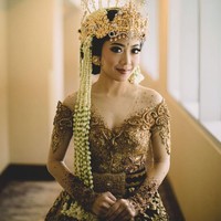 Jika kebanyakan artis memilih mengenakan kebaya berwarna putih, maka berbeda dengan Karina Salim. Memilih adat Sunda untuk hari pernikahannya, Karina tampil cantik dalam balutan kebaya berwarna coklat keemasan. Kebaya dengan model semi sabrina itu tampak dihiasi dengan payet dan manik-manik. Penampilan Karina pun semakin memukau dengan siger Sunda di kepalanya. Foto: Instagram