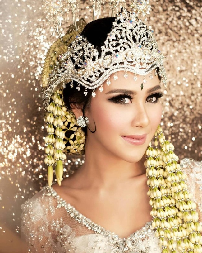 Syahnaz Sadiqah juga memilih mengenakan kebaya pengantin Sunda berwarna putih. Kebaya yang dikenakan oleh Syahnaz itu tampak dipenuhi oleh payet. Bagian kerah lehernya dihiasi dengan manik-manik. Tak lupa Syahnaz juga mengenakan siger yang dipadukan dengan ronce untuk menghiasi kepalanya. Foto: Instagram