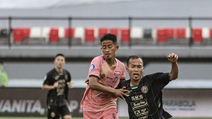 Pemain PSS Sleman Syaiful Ramadhan (baju hitam) berjibaku mengamankan bola dari kejaran pemain Madura United.