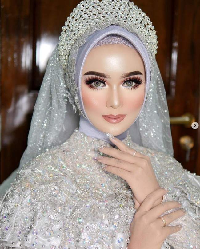 Rias makeup dengan tema Barbie Look bisa membuat kamu tampil pangling di hari pernikahan. Pemakaian bulu mata bawah dan atas berlapis menjadi kunci dari tampilan makeup Barbie Look. Ditambah dengan contour di bagian tulang pipi dan highlighter yang on point. Foto: Dok. Instagram @khadijahazzahra_makeup.