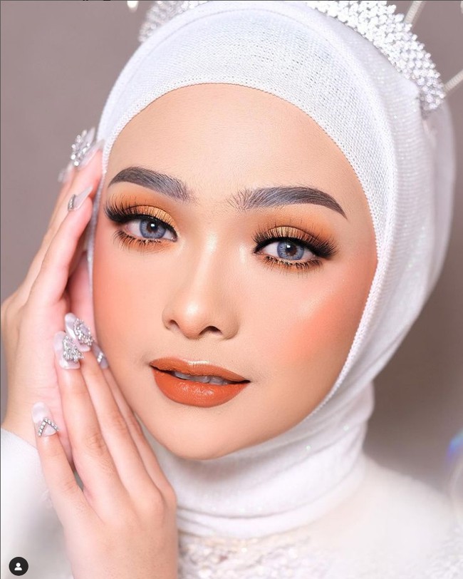 Tren makeup sunset eyes belakangan diminati oleh pengantin saat hari pernikahan. MUA Dini Nurdiani Sugiharta membuat riasan sunset eyes dengan monochromatic look terlihat lebih hidup jika dikombinasikan dengan softlens warna biru atau abu-abu. Foto: Dok. Instagram @bydininurdiani.