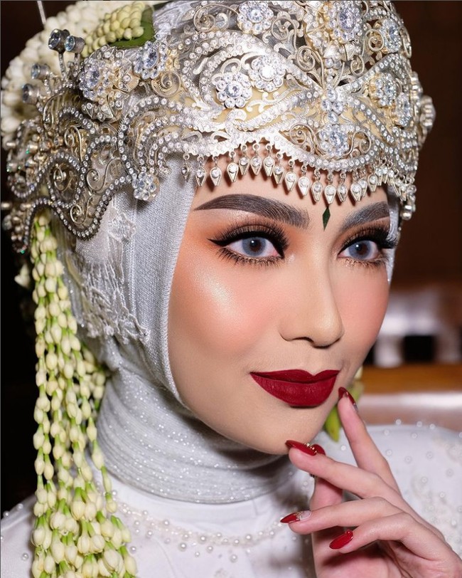 Inspirasi rias pengantin hijab berikutnya adalah makeup bold. Jenis riasan ini termasuk favorit bagi pengantin yang ingin menikah. Seperti dalam foto ini tampilan pengantin terkesan mewah dan elegan. Foto: Dok. Instagram @nanathnadia.