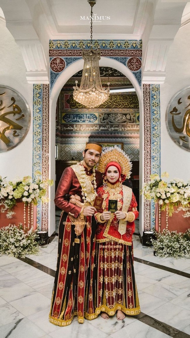 Berlokasi di Masjid Cut Meutia, Menteng, Jakarta Pusat, prosesi akad nikah Achmad Megantara dan Asri Faradila tampak didominasi warna merah. Berikut foto keduanya saat memegang buku nikah. Walaupun memiliki perbedaan usia 6 tahun, namun keduanya tetap terlihat serasi. Asri Faradila diketahui 6 tahun lebih muda, usianya sekitar 18 tahun. Foto: Instagram