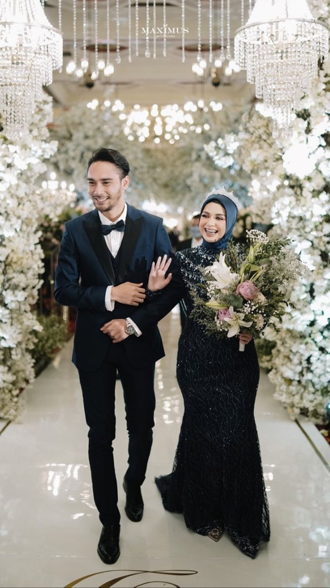 Untuk resepsi pernikahan, Achmad Megantara dan Asri Faradila memilih tema internasional. Keduanya tampil kompak mengenakan busana berwarna biru tua. Senyum sumringah pun tampak terpancar dari wajah pengantin baru ini. Foto: Instagram