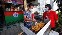 Pemilik memanggang sate daging buaya di restorannya.