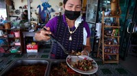 Seorang koki menyajikan hidangan yang dibuat dengan daging buaya di restoran.