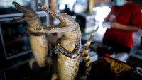 Boneka buaya berpose dalam salam tradisional Thailand untuk dijual di restoran