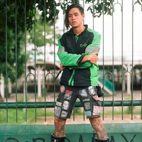 Berkunjung ke Indonesia, Arnold Putra sempat foto OOTD dengan jaket ojol. Ia memadukannya dengan boots tinggi hitam Balenciaga. (Foto: Instagram/@arnoldputra)