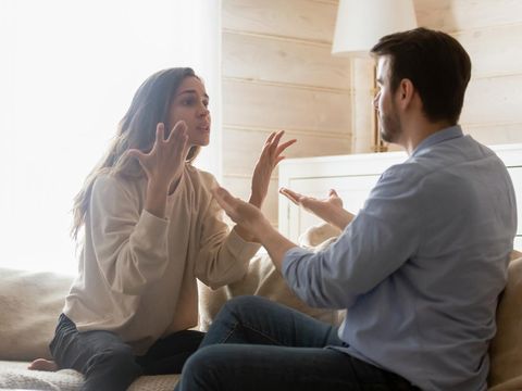 Angry young couple sit on couch in living room having family fight or quarrel suffer from misunderstanding, millennial husband and wife dispute involved in argument, relationships problems concept