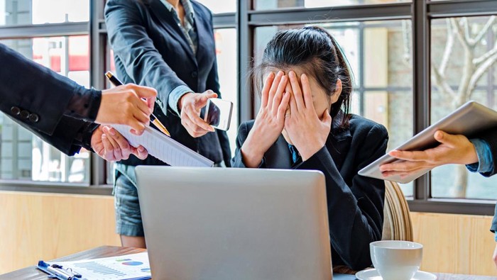 Female office worker with too many tasks to take at the same time.