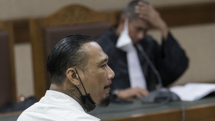 Terdakwa yang juga musisi I Gede Ari Astina atau Jerinx Superman is Dead (SID) (kedua kanan, atas) menyimak keterangan salah satu saksi dalam sidang lanjutan kasus pengancaman melalui media elektronik pada Adam Deni di Pengadilan Negeri (PN) Jakarta Pusat, Jakarta, Selasa (25/1/2022). Sidang beragendakan mendengarkan keterangan tiga saksi ahli bidang ahli pidana, digital forensik dan ITE yang dihadirkan jaksa penuntut umum. ANTARA FOTO/Aditya Pradana Putra/hp.