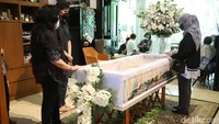 Tampak peti jenazah dengan salib bunga berwarna putih di tengah ruangan rumah duka. (Foto: Palevi/detikcom)