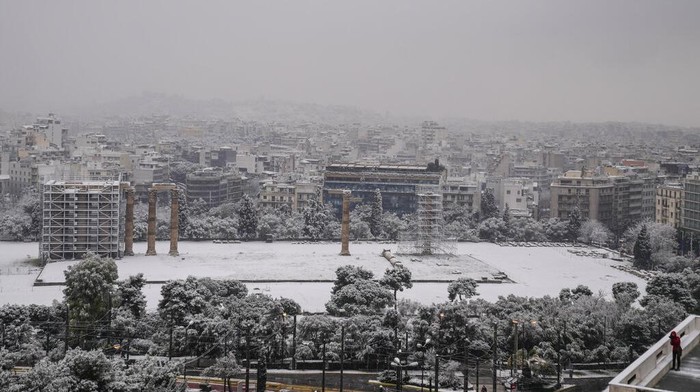 Salju Yunani People walk on the snow-covered Syntagma square during snowstorm in Athens, Greece, Monday, Jan. 24, 2022. Heavy snowfall has disrupted air traffic in the Greek capital of Athens and in neighboring Turkey's largest city of Istanbul, while several Aegean islands and much of Turkey are blanketed by snow. (AP Photo/Thanassis Stavrakis)