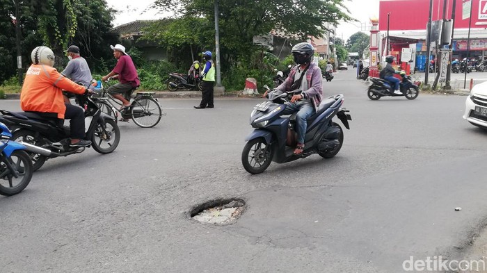 Sejumlah pengendara melintas di jalan yang berlubang di depan SMAN 7 Solo, Selasa (25/1/2022).