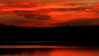 Seseorang menikmati matahari tenggelam di Danau Shawnee Mission, Kanada (18/1/2022). Senja merah tersebut sangat digemari oleh para pemburu senja. (AP Photo/Charlie Riedel)
