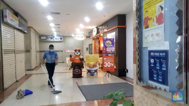 Petugas kebersihan mengepel lantai di kawasan mall Ambassador, Jakarta, Selasa, 25/1/2022. Pandemi Covid-19 telah membuat industri ritel, terutama pusat perbelanjaan sulit untuk bangkit. Mutasi baru varian Covid-19 yang terus menerus muncul membuat orang kini lebih memilih untuk tidak bepergian. Akibatnya, mal-mal di DKI Jakarta seperti di kawasan Mall Ambassador Jakarta Selatan Di mana pusat perbelanjaan tersebut kebanyakan berisi pedagang elektronik, seperti handphone, laptop, kamera, serta aksesoris lain. Kini harus menghadapi kenyataan sepi pengunjung. Banyak kini kios-kios di sejumlah pusat perbelanjaan di DKI Jakarta dijual atau disewakan.Saat CNBC Indonesia menyambangi Mal Ambassador yang kebanyakan berisi pedagang elektronik, ada beberapa toko yang tutup di lantai 3. Terlihat pada gerai toko itu terpampang selembaran info bahwa toko tersebut hendak dijual ataupun disewakan. Meskipun pembeli terlihat cukup ramai di lantai dasar. Salah satu pedagang, Bjeh mengatakan bahwa tutupnya beberapa toko ini, karena jarangnya pembeli. Oleh karenanya pedagang harus rela meninggalkan tokonya tersebut. Berdasarkan pengamatan CNBC Indonesia, memang banyak gerai yang dijual hingga dikontrakkan ke penyewa yang berminat. Namun, itu bukan perkara mudah karena banyak pelaku usaha yang menahan dana untuk tidak berinvestasi di pusat perbelanjaan. Menanggapi fenomena mal-mal legendaris di Jakarta yang sepi, Ketua Umum Himpunan Penyewa Pusat Perbelanjaan Indonesia Budihardjo Iduansjah mengungkapkan, banyaknya tenant atau penyewa menutup gerai disebabkan ekosistem ekonomi di mal itu sudah tidak lagi bergairah. (CNBC Indonesia/ Muhammad Sabki)