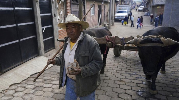 A community police officer stands guard at the main gate to the Purepecha Indigenous community of Comachuen, Michoacan state, Mexico, Wednesday, Jan. 19, 2022. In Comachuen the whole town survives because of the money sent home by migrants working in the United States. (AP Photo/Fernando Llano)