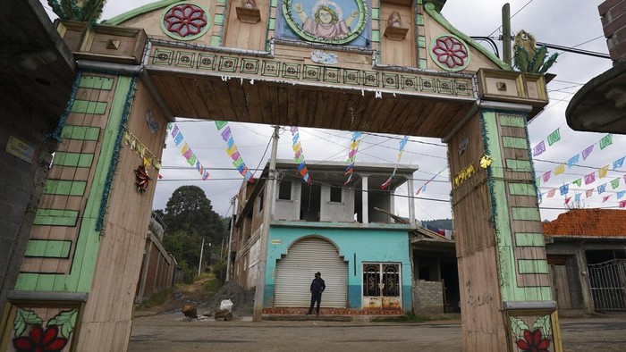 A community police officer stands guard at the main gate to the Purepecha Indigenous community of Comachuen, Michoacan state, Mexico, Wednesday, Jan. 19, 2022. In Comachuen the whole town survives because of the money sent home by migrants working in the United States. (AP Photo/Fernando Llano)