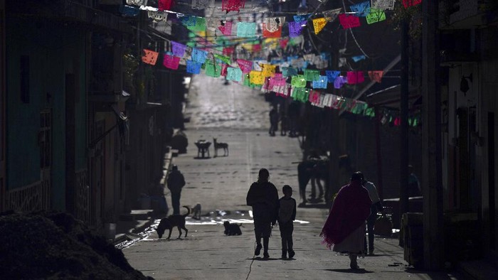 A community police officer stands guard at the main gate to the Purepecha Indigenous community of Comachuen, Michoacan state, Mexico, Wednesday, Jan. 19, 2022. In Comachuen the whole town survives because of the money sent home by migrants working in the United States. (AP Photo/Fernando Llano)