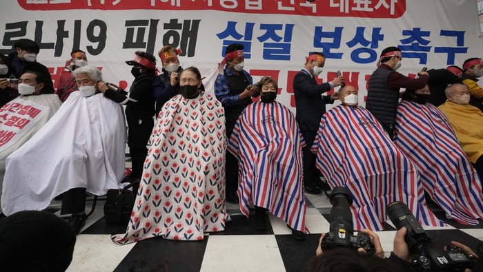 Small business owners have their heads shaved during a rally against the government's social distancing rules near the National Assembly in Seoul, South Korea, Tuesday, Jan. 25, 2022. South Korea recorded more than 8,000 new coronavirus infections for the first time Tuesday as health authorities reshape the country's pandemic response to address a surge driven by the highly contagious omicron variant. (AP Photo/Ahn Young-joon)