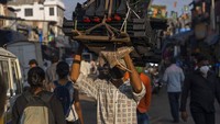 Seorang buruh harian membawa kotak besar di dekat pabrik, di Dharavi, Mumbai, India, (18/1/2022). Populasi India yang mencapai 1,3 miliar jiwa membuat kehidupan sangat dinamis. (AP Photo/Rafiq Maqbool)
