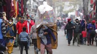 Pedagang mainan membawa lapaknya dengan tali yang diikat ke kepala, di Pasar Jammu, India (21/1/2022). Jammu merupakan wilayah di sebelah utara India dengan iklim subtropis. Cuaca dingin pada awal tahun memuat penduduk bekerja ekstra keras untuk tetap bertahan. (AP Photo/Channi Anand)