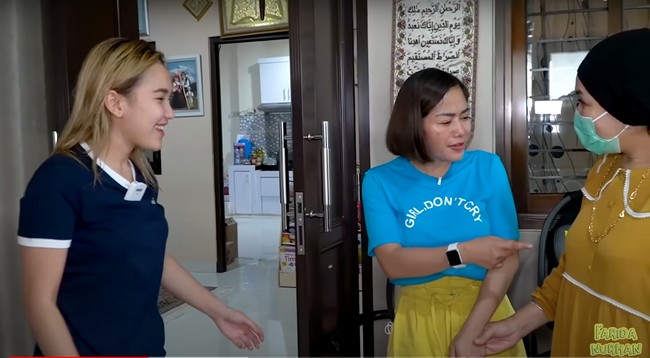 Umi Kalsum tampak berpenampilan santai dengan mengenakan dress berwarna mustard. Namun rupanya aksesori yang dikenakan oleh Umi Kalsum itu membuat Farida menjadi salfok. Dengan ekspresi terkejut, Farida pun terlihat menunjuk kalung yang melingkar di leher umi Kalsum. Foto: YouTube/Farida Nurhan