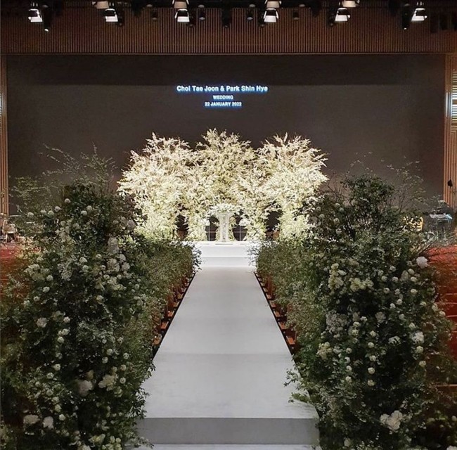 Bagian selasar di mana pengantin wanita berjalan menuju altar pun dihiasi bunga putih dan rangkaian tanaman hijau. Foto: Instagram/@grove008, Soulpage Photography