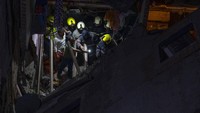 Petugas pemadam kebakaran dan warga membersihkan puing-puing gedung yang ambruk.