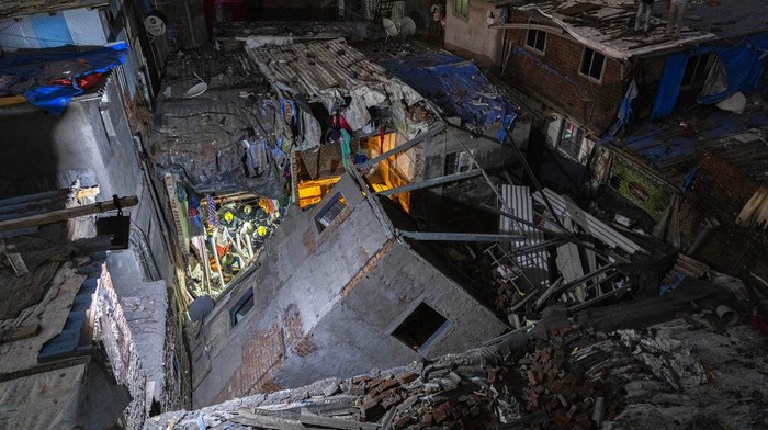 Fire brigade personnel along with others clear debris after a 5-story building collapsed at a slum in Mumbai, India, Wednesday, Jan. 26, 2022. (AP Photo/Rafiq Maqbool)