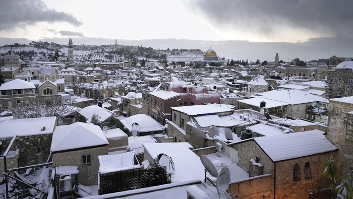 The Western Wall, right, and the Dome of the Rock, among the holiest sites for Jews and Muslims, are covered in snow, in Jerusalem Old city, Thursday, Jan. 27, 2022. A rare snowfall hit parts of Israel and the West Bank, closing schools and businesses. (AP Photo/Mahmoud Illean)
