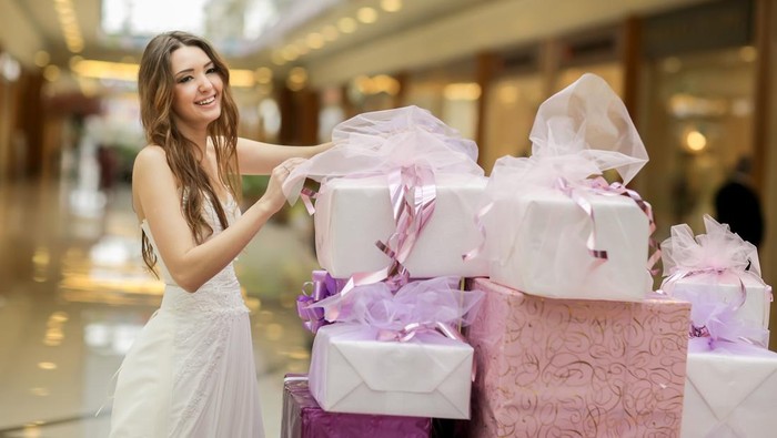 smiling bride in a white dress holds a box with gifts