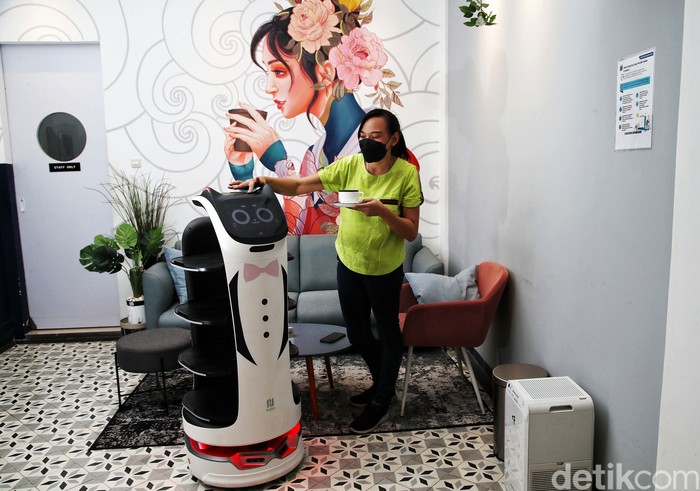 Barista mengoperasikan robot saat mengantar kopi kepada pembeli di kawasan Kafe Rasa Koffie, Pasar Baru, Rabu (26/1). Kafe yang dibangun pada 2020 itu menggunakan robot sebagai pelayan pembeli.