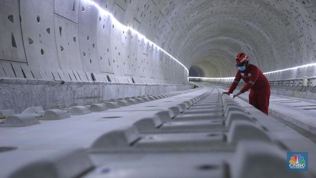 Pekerja Mengerjakan Proyek Tunnel #1 Kereta Cepat Jakarta Bandung Sepanjang 1.885 meter atau 1,8 kilometer yang berlokasi di Jalan Tol Jakarta-Cikampek KM 5+500, Kamis, (27/1/2022). Tunnel 1 merupakan terowongan dengan dua lintasan kereta cepat yang berlokasi di area Halim dan berjarak 2.5 kilometer dari Stasiun Kereta Cepat.Tunnel 1 dirancang sepanjang 1.885 meter dan dibangun dengan metode Tunnel Boring Machine (TBM). Terowongan ini melintang menembus bagian bawah Jalan Tol Jakarta-Cikampek.Pembangunan proyek Tunnel 1 ini dilakukan menggunakan mesin bor atau Tunnel Boring Machine (TBM). TBM merupakan mesin bor pembuat terowongan yang didatangkan langsung dari negeri China, untuk membuat struktur Tunnel 1 Kereta Cepat Jakarta Bandung. TBM yang digunakan memiliki diameter 13,23 meter dengan panjang 102,3 meter, berat 2.600 ton dan menjadi mesin bor TBM terbesar se-Asia Tenggara.TBM kereta cepat ini beroperasi menggali struktur tunnel 1 dengan rata-rata 113 meter per bulan. Saat beroperasi maksimum, TBM kereta cepat mampu menggali hingga 322 meter dalam satu bulan.Ukuran TBM yang sangat besar ini diganjar Museum Rekor Dunia Indonesia (MURI) sebagai mesin bor terbesar penggali terowongan yang ada di Indonesia. Dari 5 tunnel yang telah dibangun untuk proyek KCJB, hanya Tunnel 1 Halim yang dibangun menggunakan mesin bor TBM. (CNBC Indonesia/ Muhammad Sabki)