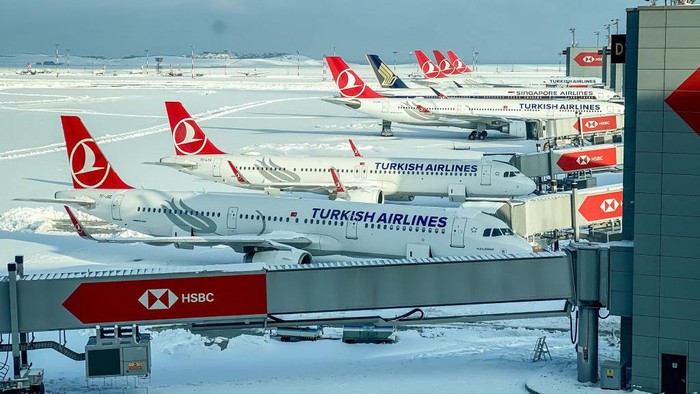 ISTANBUL, TURKEY - JANUARY 26: Turkish Airlines planes are seen parked at gates amid heavy snow at Istanbul Airport on January 26, 2022 in Istanbul, Turkey. A large storm brought wintery weather across Istanbul, covering the city in heavy snowfall and causing the closure of Istanbul Airport on January 24 and 25.  All flights were cancelled as the airport, one of Europes busiest, shut down and stranded thousands of passengers. The shutdown is the first for the new airport since operations were moved from Ataturk Airport in 2019. Operations have resumed at limited capacity with passengers facing long delays as grounds crews and airport staff struggle to clear snow and rebook flights.  (Photo by Chris McGrath/Getty Images)