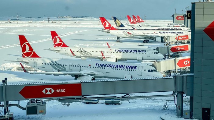 Potret Bandara Istanbul Tertutup Salju Tebal ISTANBUL, TURKEY - JANUARY 26: Turkish Airlines planes are seen parked at gates amid heavy snow at Istanbul Airport on January 26, 2022 in Istanbul, Turkey. A large storm brought wintery weather across Istanbul, covering the city in heavy snowfall and causing the closure of Istanbul Airport on January 24 and 25. All flights were cancelled as the airport, one of Europe's busiest, shut down and stranded thousands of passengers. The shutdown is the first for the new airport since operations were moved from Ataturk Airport in 2019. Operations have resumed at limited capacity with passengers facing long delays as grounds crews and airport staff struggle to clear snow and rebook flights. (Photo by Chris McGrath/Getty Images)