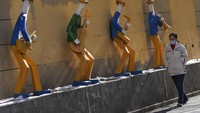 Warga sendiran melintas di depan karya seni instalasi di Beijing (25/1/2022).  (AP Photo/Andy Wong) 