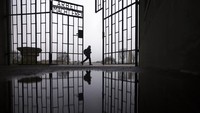 Warga melintas di gerbang peringatan korban Nazi di Oranienburg, sekitar 30 km sebelah utara Berlin, Jerman (27/1/2022). (AP Photo/Markus Schreiber)