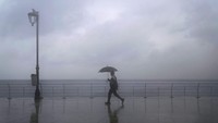 Pejalan kaki menggunakan payung, sendirian menembus hujan lebat dengan latar Laut Mediterania, di Beirut, Lebanon (26/1/2022).  (AP Photo/Hassan Ammar)
