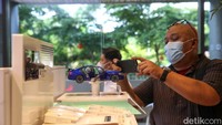 Pengunjung tengah memotret miniatur mobil BMW.