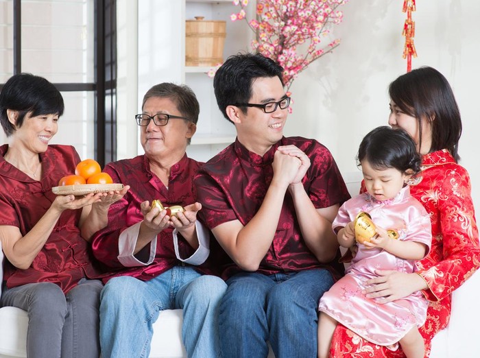 Ilustrasi Pantangan Imlek Celebrating Chinese new year. Happy Asian multi generations family in red cheongsam reunion and greeting at home.