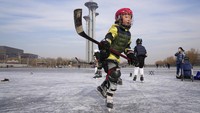 Seorang anak berlatih hoki es di dekat Menara Olimpiade Beijing di Beijing, Cina, Selasa, (18/1/2022). Sekolah umum menambahkan skating dan olahraga musim dingin lainnya dalam kurikulum pelajaran.