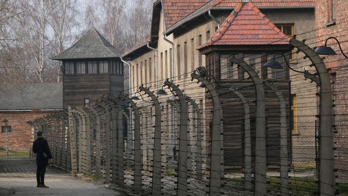 OSWIECIM, POLAND - JANUARY 26: A visitor walks among barbed wire and prison barracks at the former Auschwitz I concentration camp on January 26, 2020 in Oswiecim, Poland. International leaders as well as approximately 200 survivors will gather at Auschwitz tomorrow to commemorate the 75th anniversary of the camps liberation. The Nazis killed an estimated one million people, mostly Jews, at the camp during World War II.   (Photo by Sean Gallup/Getty Images)