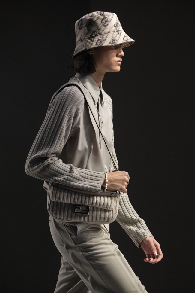 Rizal Rama mendapat kepercayaan untuk memeragakan look monokrom serba abu-abu yang terdiri dari kemeja dan celana panjang senada. Gayanya disempurnakan dengan tas Baguette Fendi yang ikonis, berikut kalung berlogo monogram FF, dan bucket hat. (Foto: Dok. Fendi)
