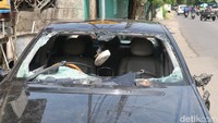 Kaca depan mobil pun menjadi sasaran amukan massa.