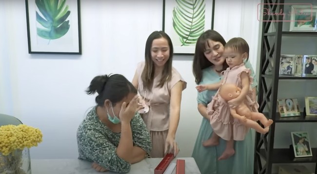 Shandy Aulia sempat mengunggah momen dirinya memberi kejutan kepada pengasuh sang anak saat pengasuh Claire itu berulang tahun. Awalnya Shandy dan timnya tampak mengerjai asistennya itu sampai menangis. Usai berhasil mengerjai sang asisten, Shandy sambil menggendong sang anak kemudian memberikan asistennya itu kue ulang tahun dan sebuah kalung emas. Foto: YouTube/Shandy Aulia